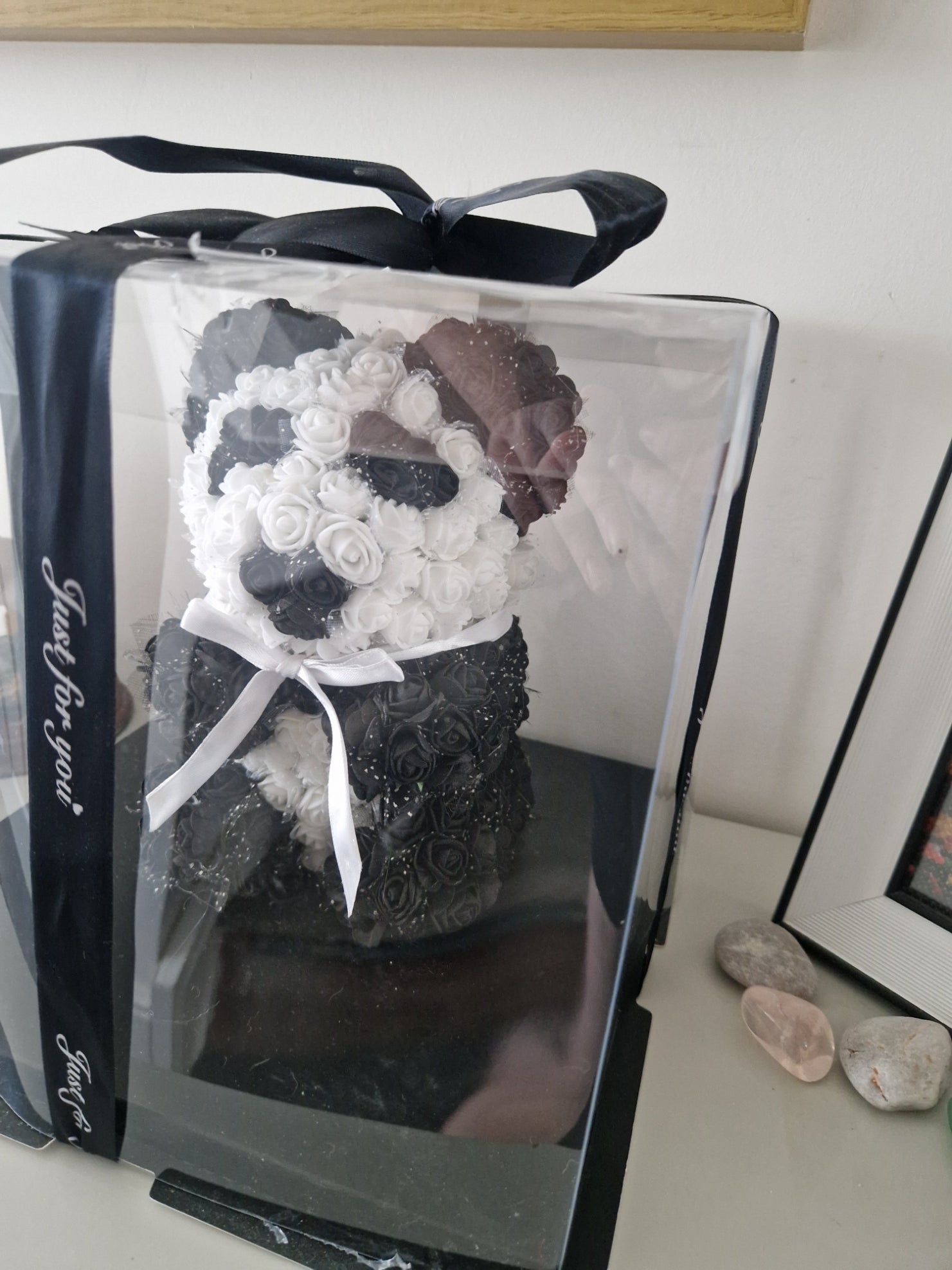 A black and white floral bridal bouquet displayed inside a clear plastic presentation box with a black ribbon handle and the words 'Just for you' printed on the front.