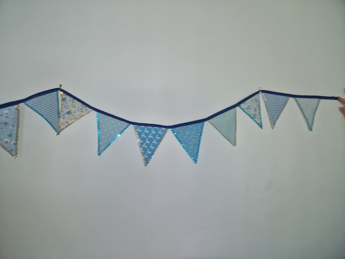 A blue bunting banner with triangular flags hanging against a plain light gray wall.
